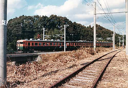 稲原駅付近の旧線跡と165系普通列車